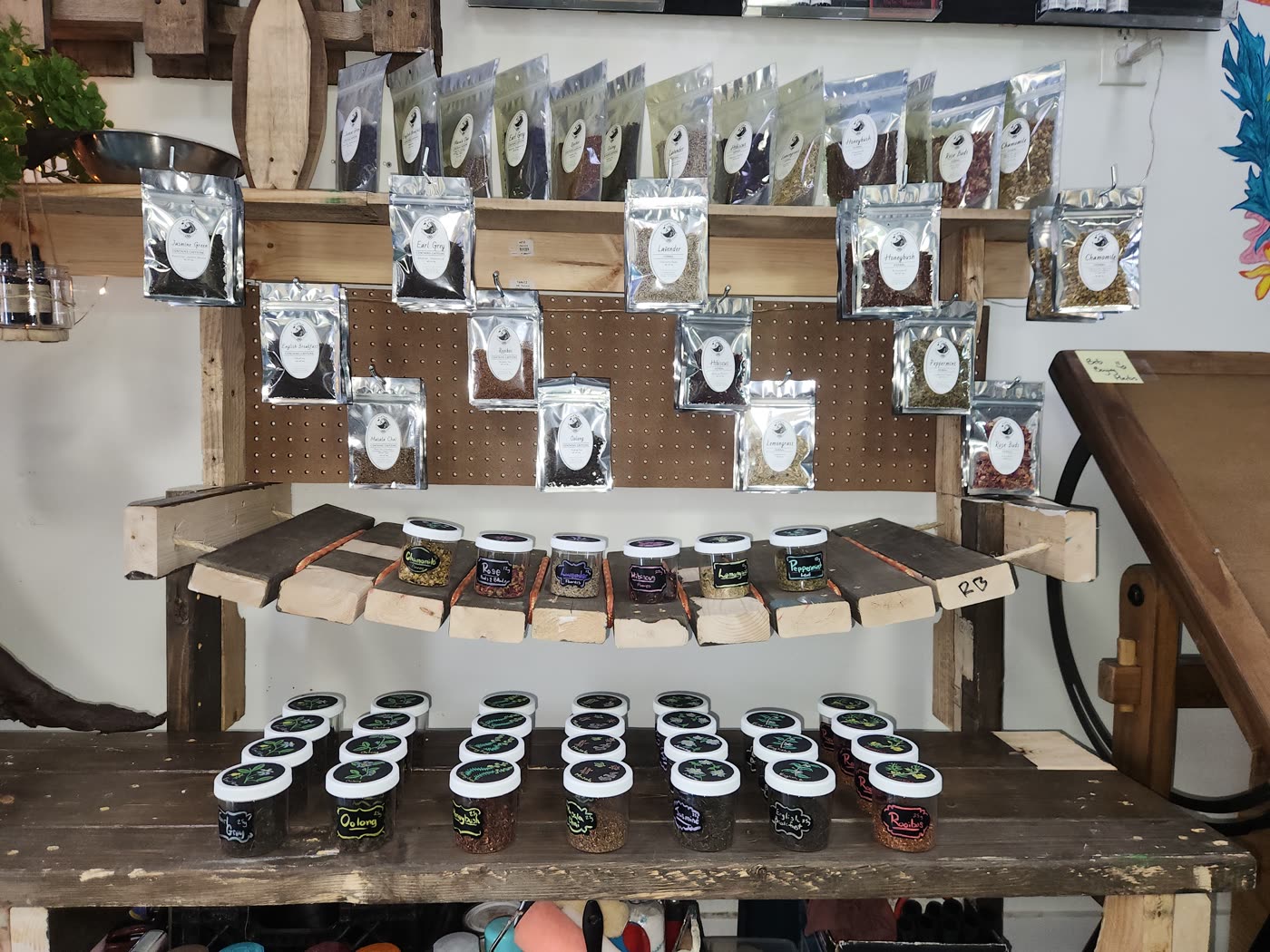 The tea wall at Swami Juice — loose leaf teas in labelled pouches hung on a reclaimed-wood and pegboard wall