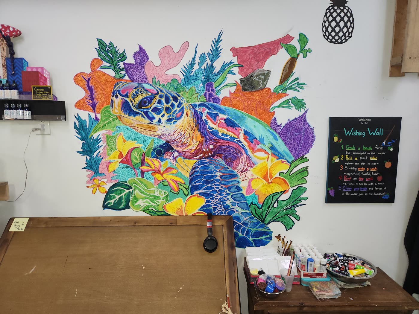 A sea turtle mural hand-painted on the studio wall at Swami Juice, surrounded by coral, seaweed and tropical flowers in full color